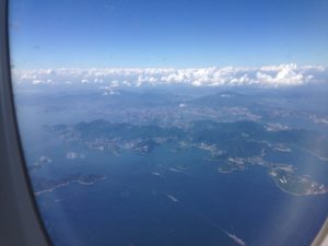View of blue sky, clouds and mountains from a plane window.